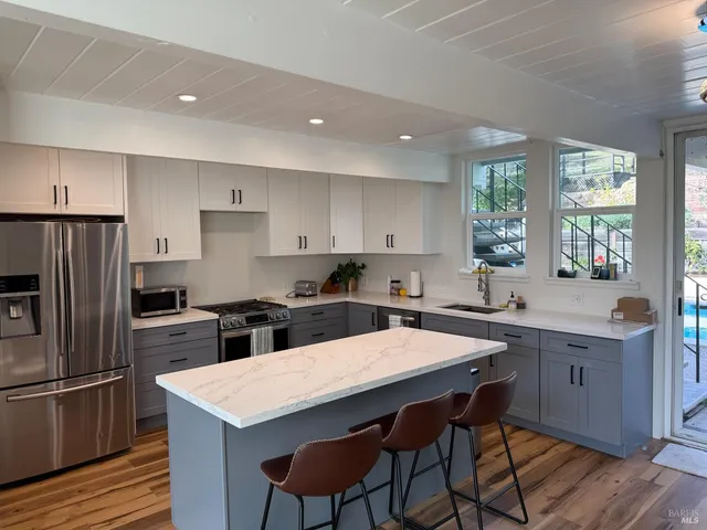 a kitchen with stainless steel appliances a table chairs sink refrigerator and cabinets