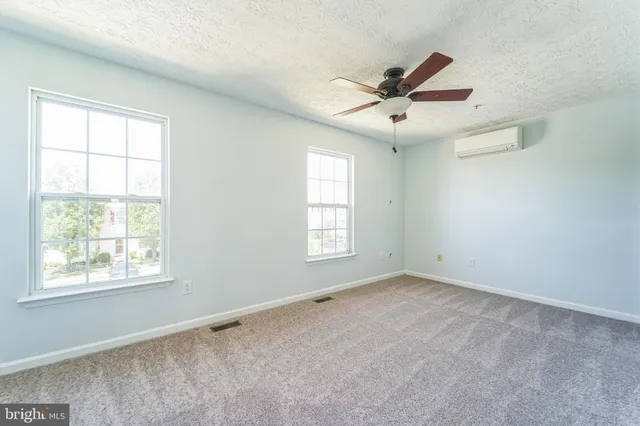 an empty room with windows and fan