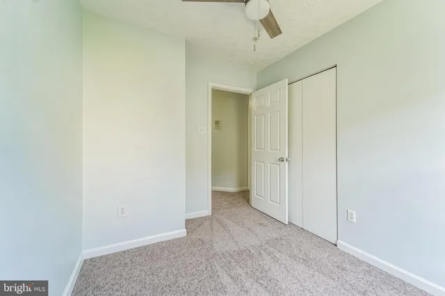 an empty room with a window and a fan