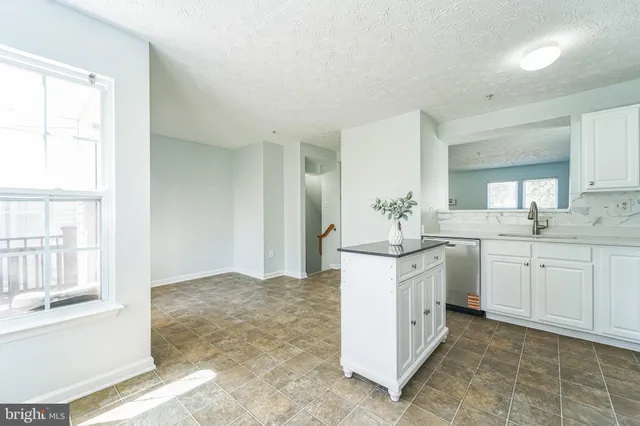 a kitchen with white cabinets and sink