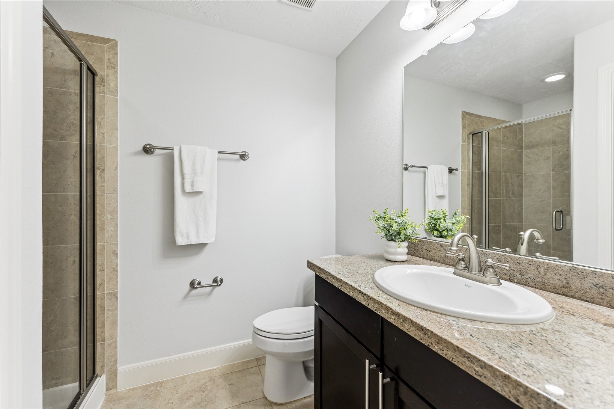 1216 Sampson Street Houston, TX 77003 - Photo 13 of 36 First floor en-suite bath includes a granite countertop vanity with under-cabinet storage and a tiled tub/shower combination with glass enclosure.
