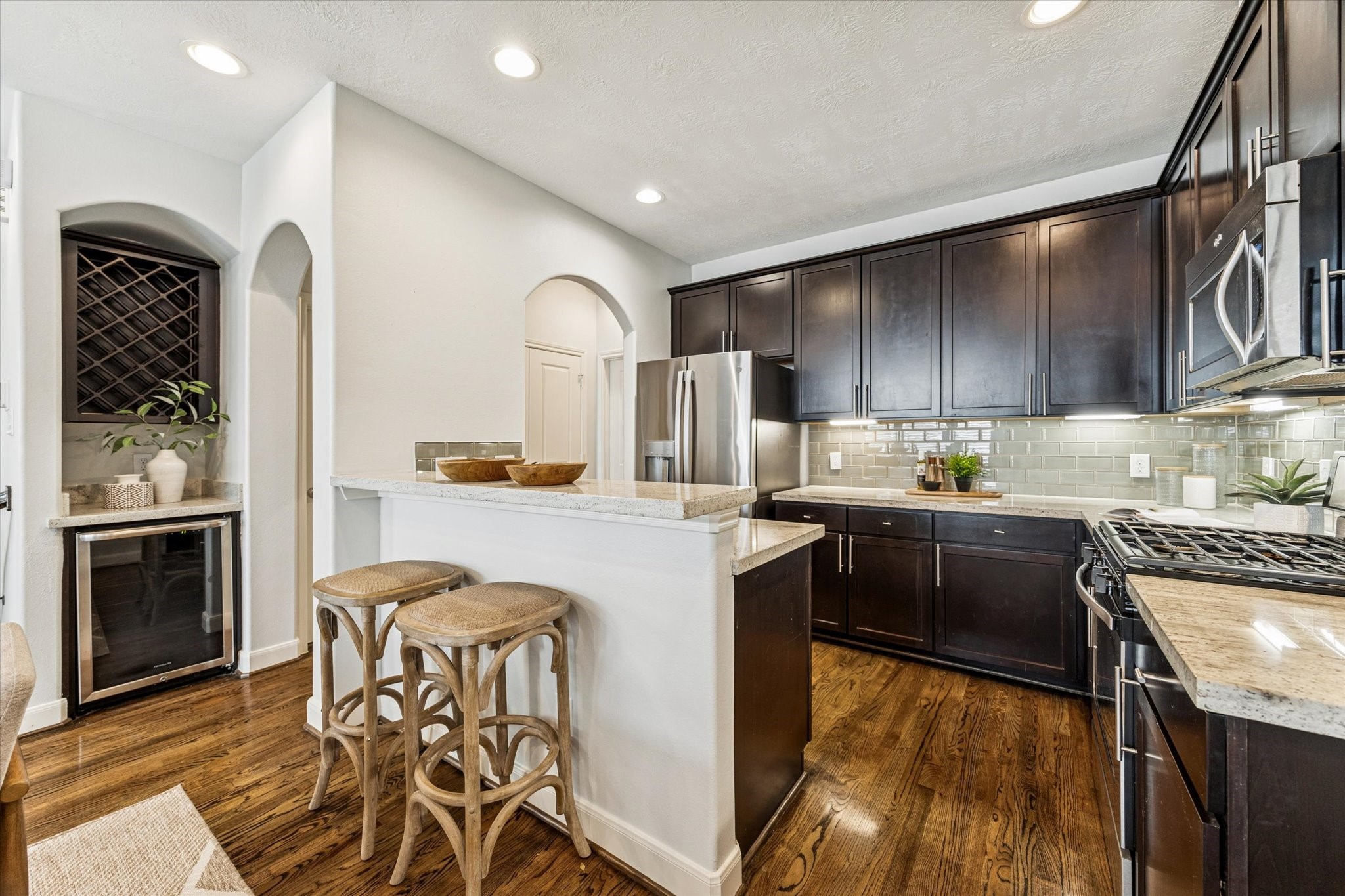 1216 Sampson Street Houston, TX 77003 - Photo 2 of 36 The kitchen features rich wood cabinetry, granite countertops, and a light subway tile backsplash for a timeless look. A raised breakfast bar provides additional seating, while under-cabinet lighting and stainless finishes enhance both function and style.