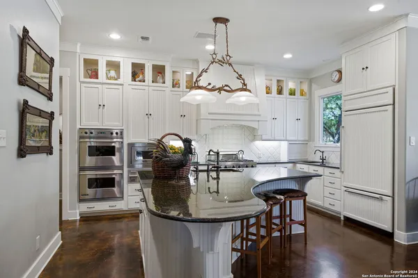 a kitchen with stainless steel appliances granite countertop a stove a refrigerator and a dining table with wooden floor