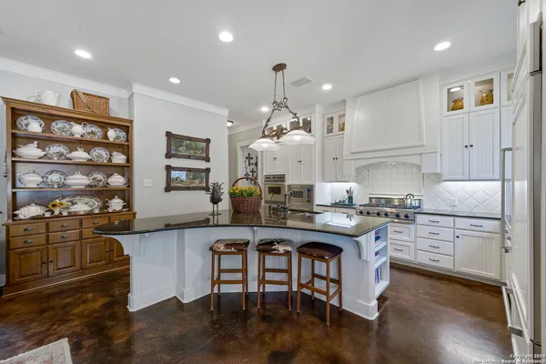 a kitchen with stainless steel appliances granite countertop a stove a sink dishwasher and a refrigerator with wooden floor