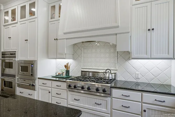 a kitchen with stainless steel appliances granite countertop white cabinets and a stove