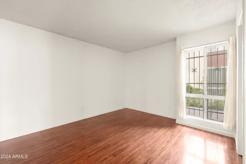 a view of empty room with wooden floor and fan