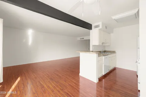 a kitchen with granite countertop white cabinets and wooden floor