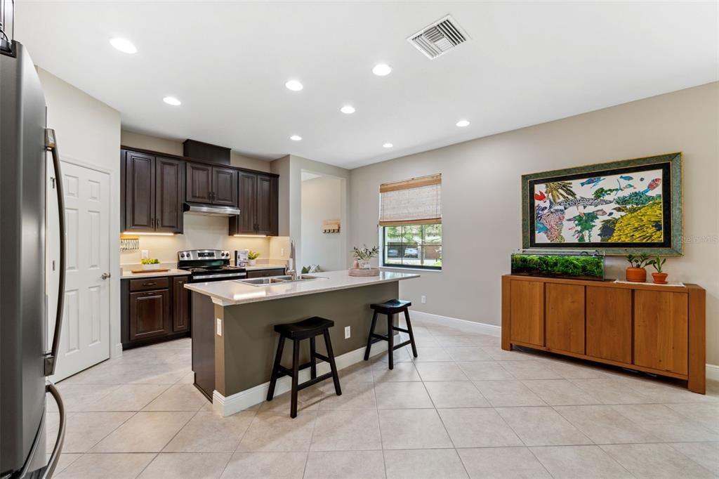 3877 Burdick Loop Odessa, FL 33556 - Photo 11 of 64 a kitchen with stainless steel appliances granite countertop a refrigerator a sink dishwasher a stove top oven a dining table and chairs with wooden floor