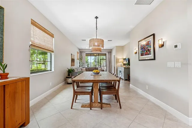 a view of a dining room and livingroom with furniture wooden floor a rug a painting and a chandelier