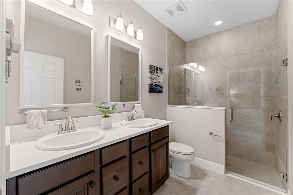 3877 Burdick Loop Odessa, FL 33556 - Photo 28 of 64 a bathroom with a double vanity sink toilet mirror and shower