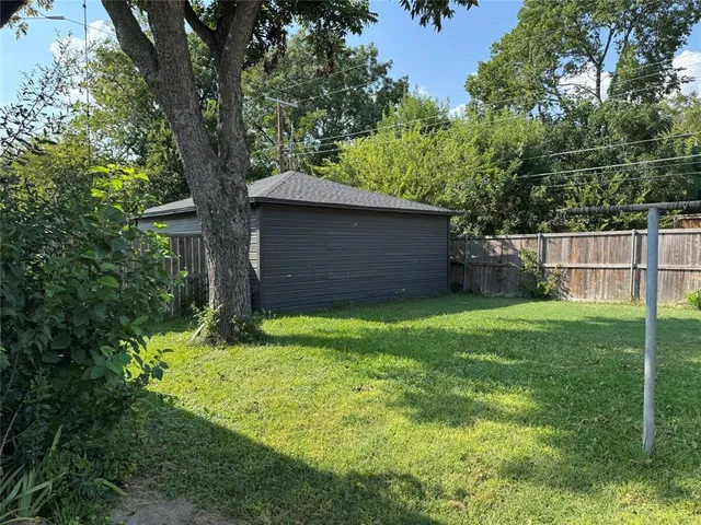 a backyard of a house with plants and large tree