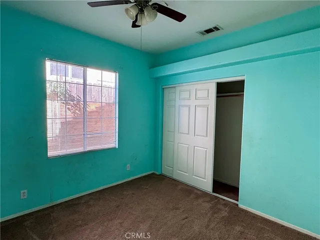 an empty room with a window and a ceiling fan