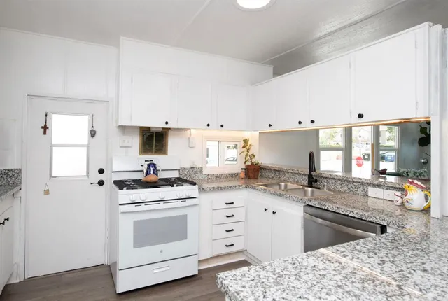 a kitchen with granite countertop a sink stove and cabinets