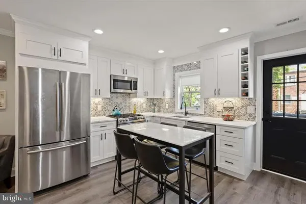 a kitchen with stainless steel appliances a refrigerator a stove a sink a dining table and chairs