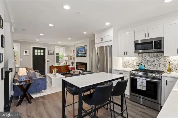 a kitchen with stainless steel appliances kitchen island granite countertop a stove a refrigerator a sink a dining table and chairs