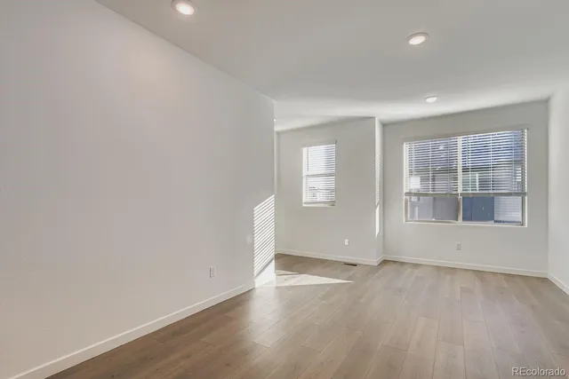 an empty room with wooden floor and windows