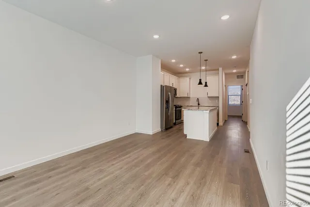 a view of a kitchen with a fridge and wooden floor