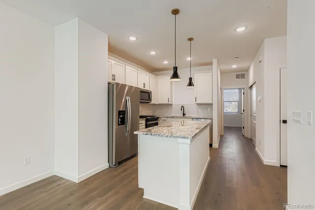 a kitchen with a refrigerator a sink and wooden floor