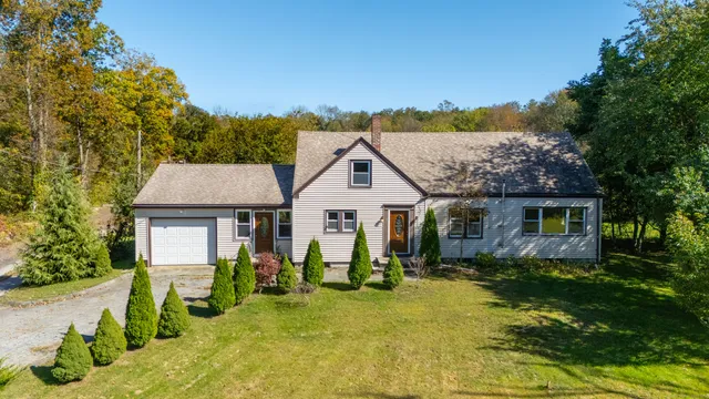 a view of a house with a big yard and large trees