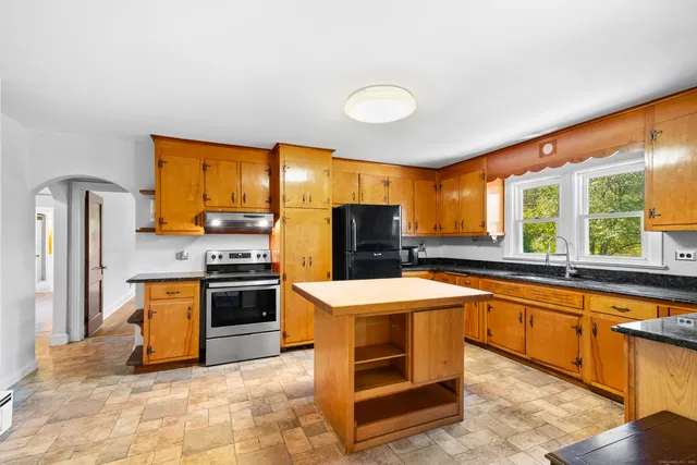 a large kitchen with stainless steel appliances granite countertop a stove refrigerator and a sink