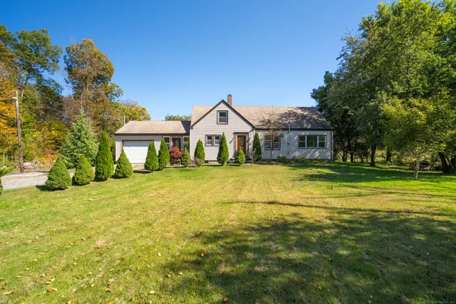 a view of a house with a big yard and large trees