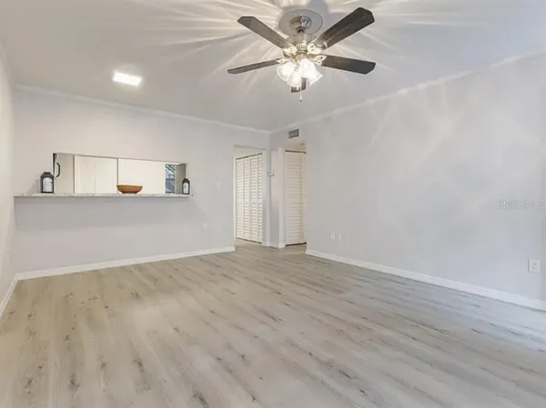 an empty room with wooden floor and ceiling fan