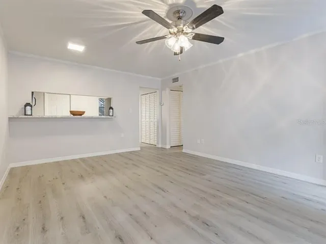 an empty room with wooden floor and ceiling fan