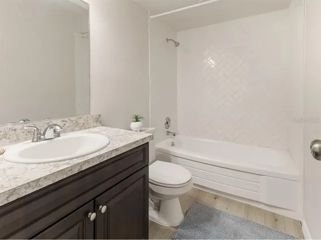 a bathroom with a granite countertop bathtub sink vanity mirror and toilet