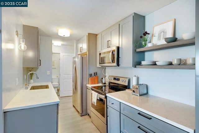a kitchen with stainless steel appliances a sink a stove a refrigerator and cabinets