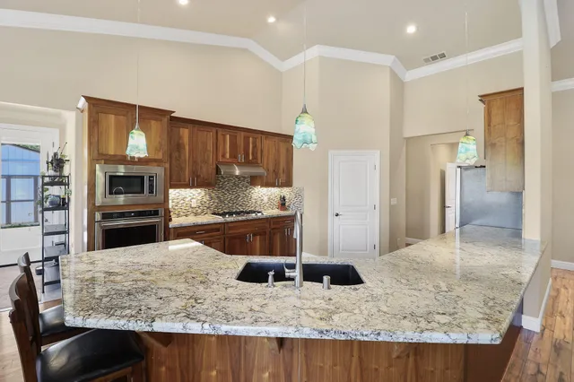 a kitchen with stainless steel appliances kitchen island granite countertop a refrigerator and stove
