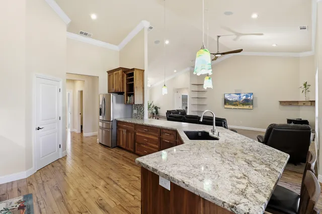 a kitchen with stainless steel appliances granite countertop a table chairs refrigerator and microwave