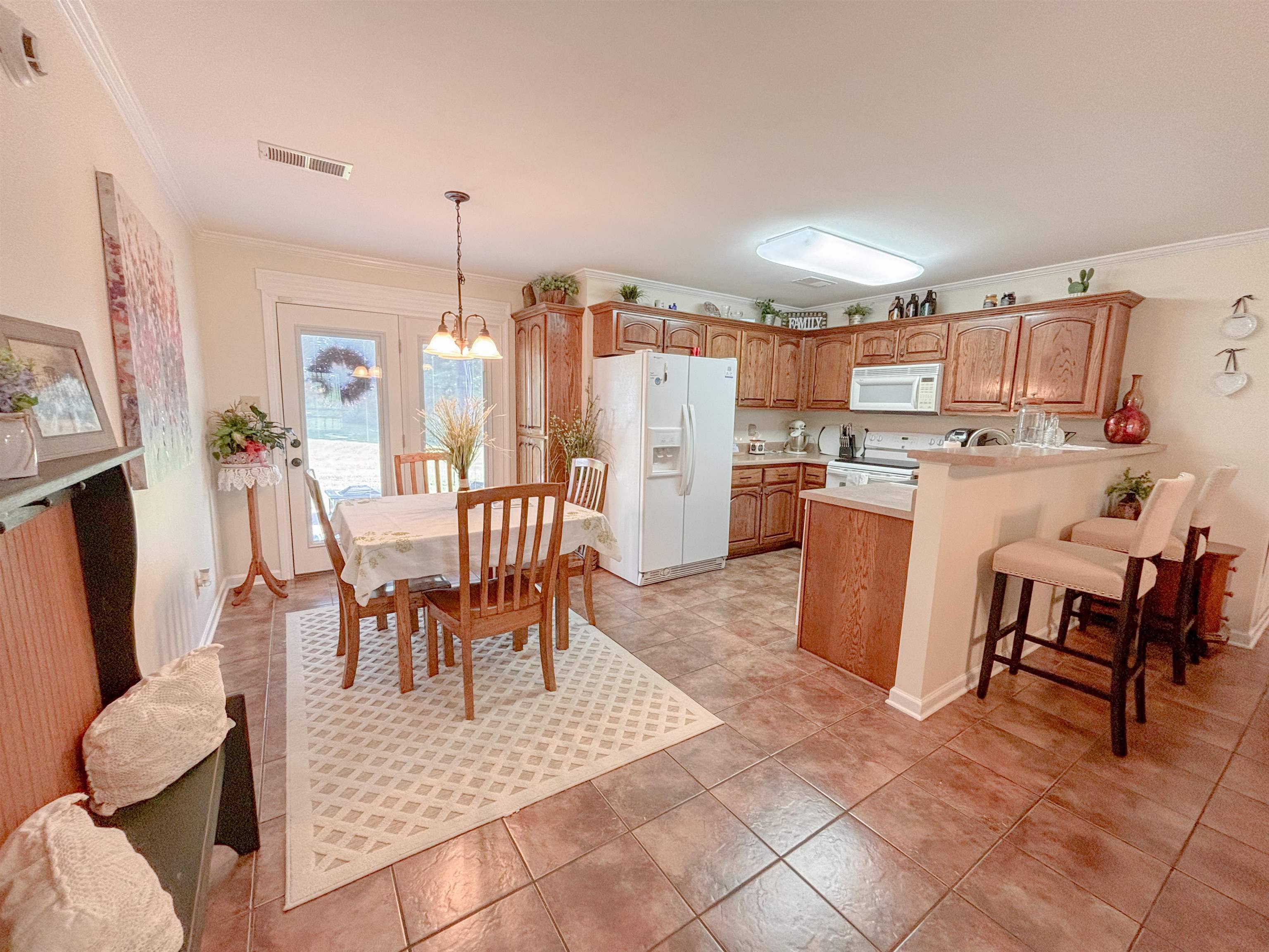 2933 Holly Grove Road Covington, TN 38019 - Photo 8 of 22 Interior space with crown molding, white appliances, decorative light fixtures, light tile floors, and a chandelier