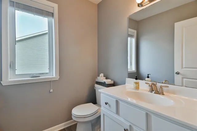 a bathroom with a toilet sink vanity and mirror