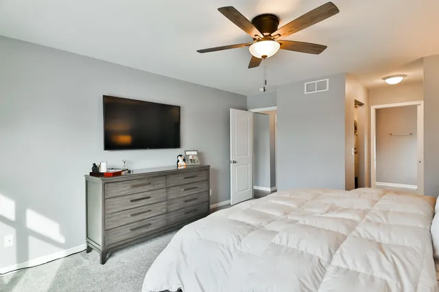 a bedroom with a bed a flat screen tv and a chandelier