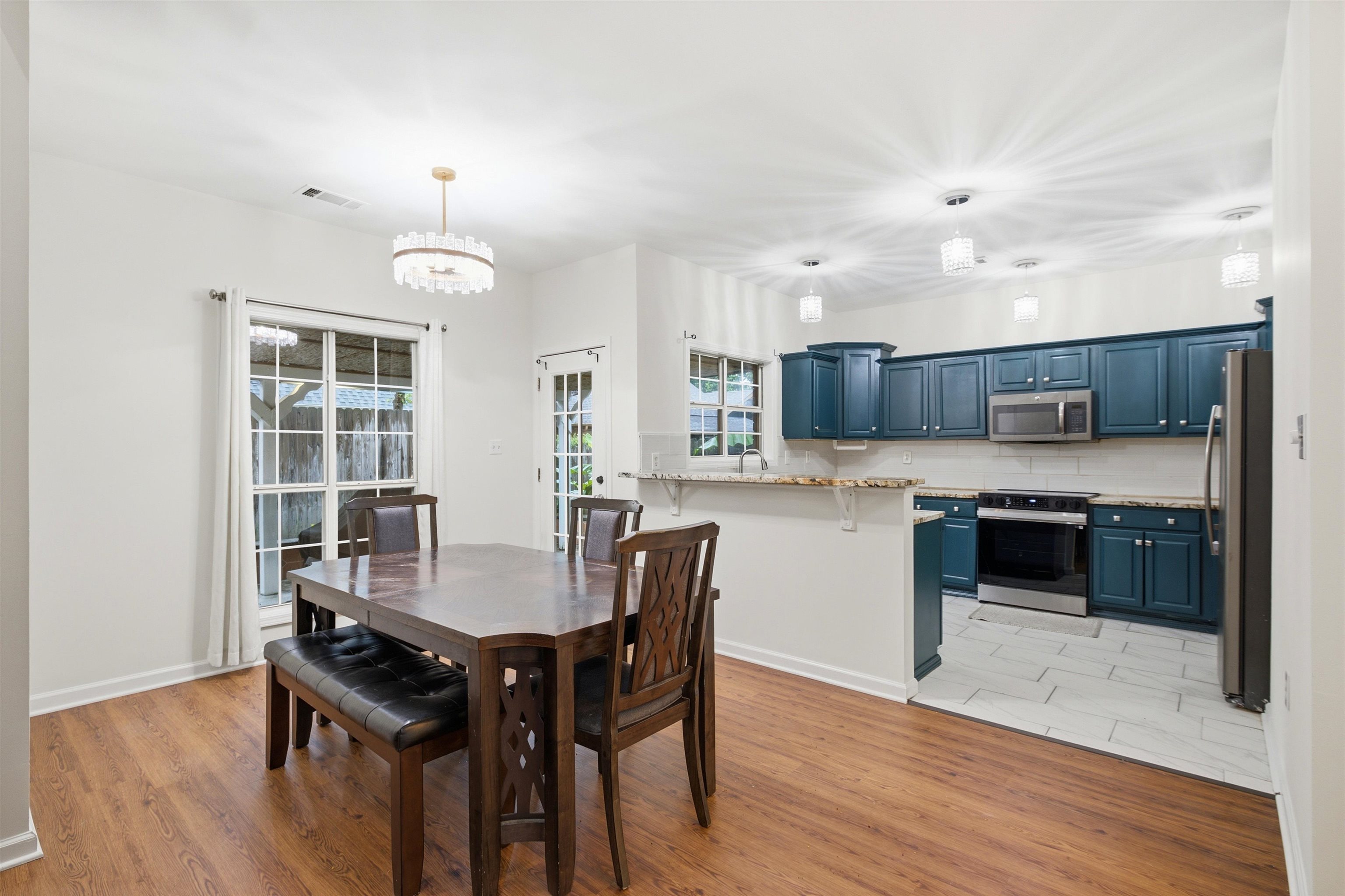 96 Berryfield Cove Collierville, TN 38017 - Photo 15 of 39 Bright kitchen and dining area featuring wood-finish flooring, white walls, and a contemporary chandelier