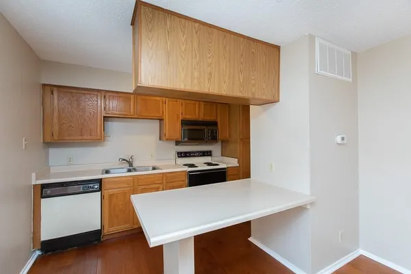 a kitchen with stainless steel appliances a stove a sink cabinets and a wooden floor