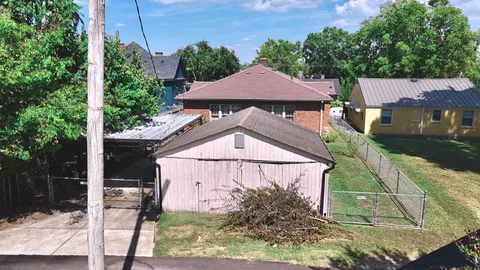 a view of a small house in front of a yard with potted plants