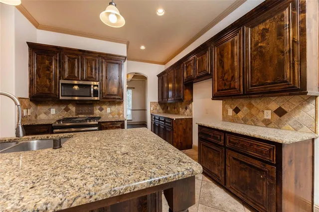 a kitchen with stainless steel appliances granite countertop wooden cabinets a stove top oven a sink and dishwasher