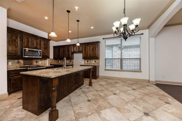 a kitchen with kitchen island granite countertop stainless steel appliances a stove center island a cabinets and a chandelier