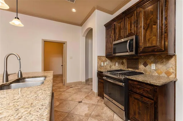 a kitchen with stainless steel appliances granite countertop a stove a sink and a microwave