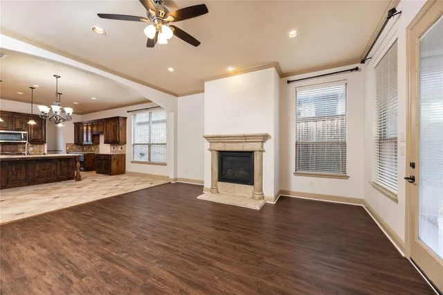 an empty room with wooden floor a ceiling fan a fireplace and windows
