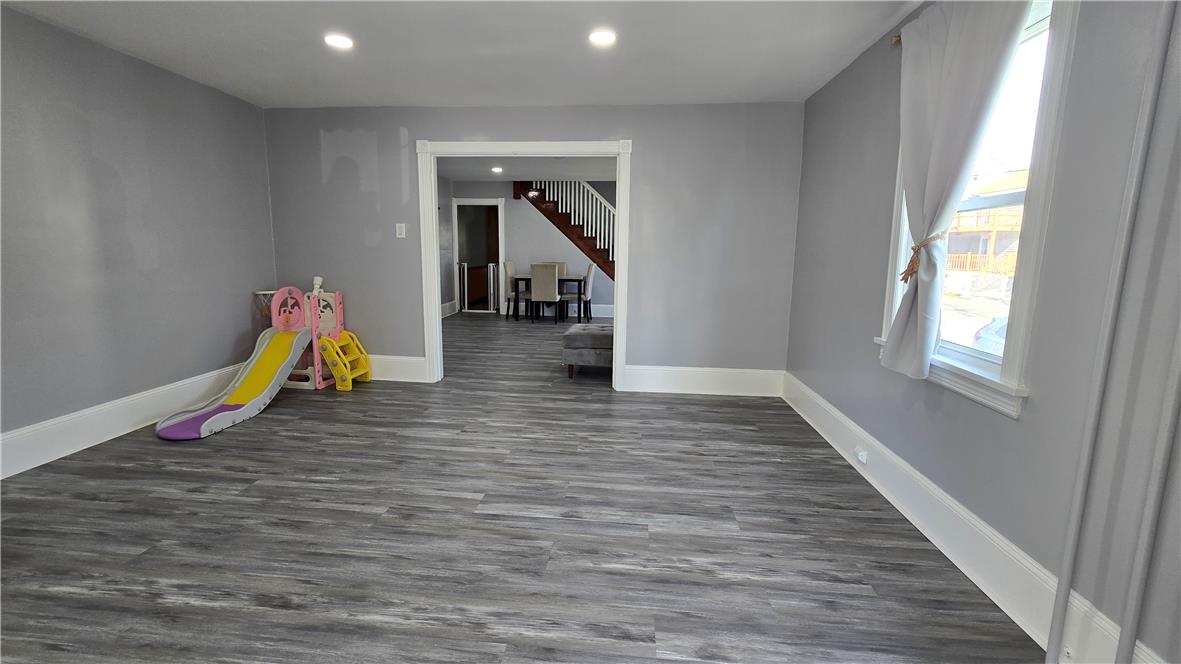 883 North Locust Street Hazleton, PA 18201 - Photo 12 of 83 A well-lit main living space, connecting to a formal dining area and a prominent staircase, all featuring resilient vinyl plank flooring.