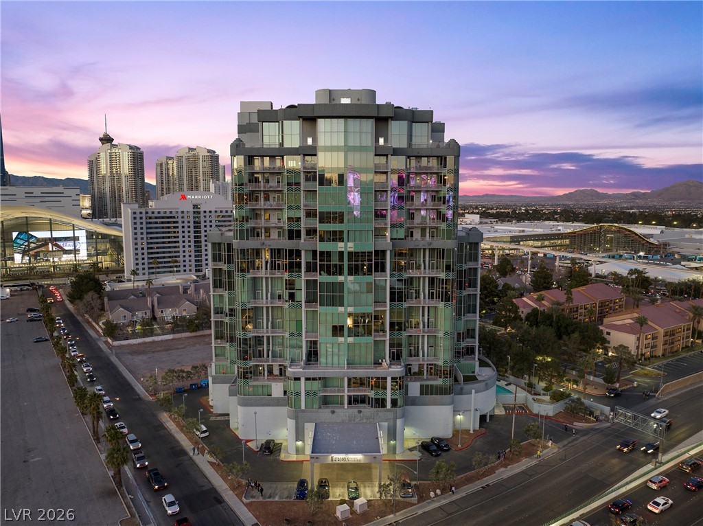 360 East Desert Inn Road, Unit 1701 Las Vegas, NV 89109 - Photo 3 of 33 An aerial perspective captures the grandeur of a modern high-rise against a vibrant sunset.