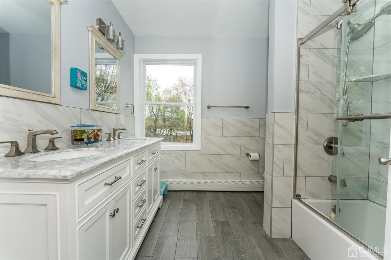 259 Spring Valley Road Morganville, NJ 07751 - Photo 30 of 36 a bathroom with a granite countertop sink a large mirror a bathtub and next to a window