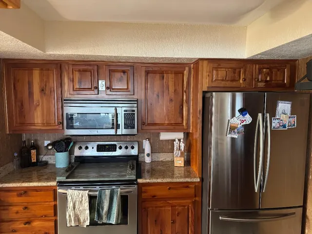 a kitchen with granite countertop a refrigerator stove and microwave