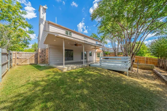 a backyard of a house with fountain plants and large tree