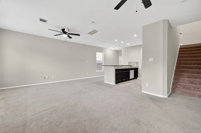an empty room with windows & ceiling fan area