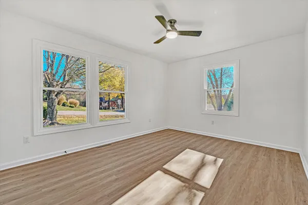 a view of an empty room with a window and wooden floor