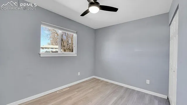 an empty room with a window and a fan