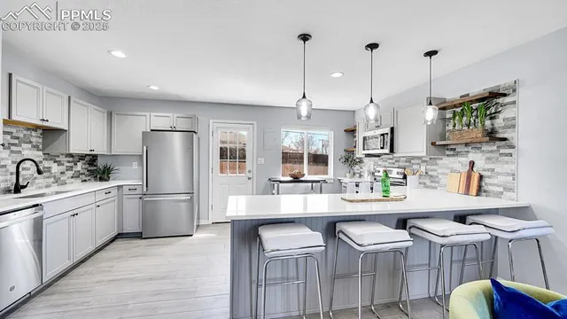 a kitchen with stainless steel appliances kitchen island granite countertop a table chairs refrigerator and sink